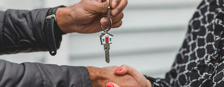 Real estate agent passing a house key to a client.