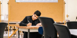 Grad student sitting at a desk working on a project for his side hustle.