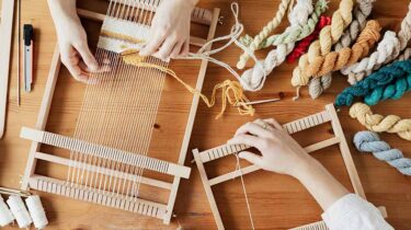 Hands of two professional crafters weaving a rug to sell for profit