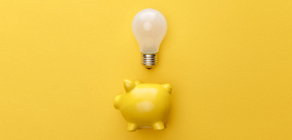 Lightbulb over a piggy bank on a yellow background