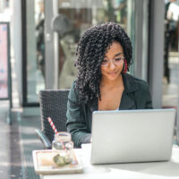 Freelancer sitting at her laptop searching for work on freelance writing websites.