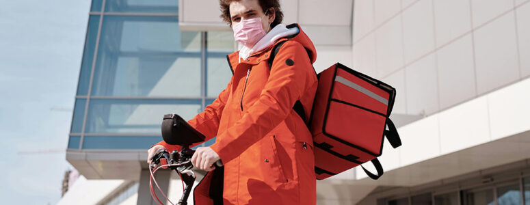 Teenage delivery driver standing beside his bicycle.