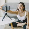 Content creator or influencer sitting cross-legged and setting up a phone on a tripod to film new content