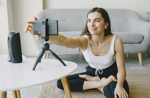 Content creator or influencer sitting cross-legged and setting up a phone on a tripod to film new content