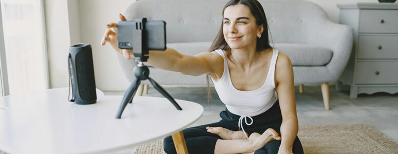 Content creator or influencer sitting cross-legged and setting up a phone on a tripod to film new content