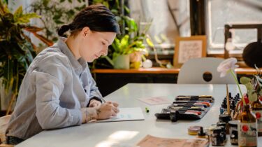 Creative side hustler sitting at a desk working on a project.