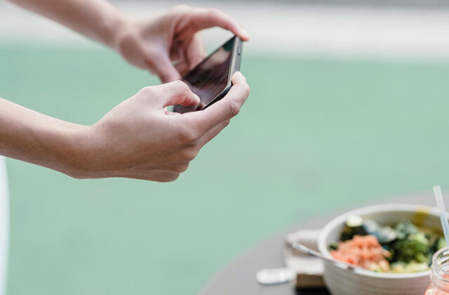 Content creator holding a phone to take a picture of food as part of their content creation side hustle