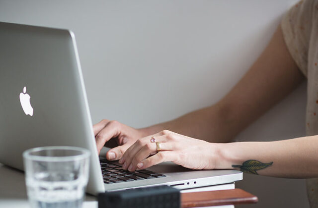 Close view of someone's hands as they edit and proofread a piece of content on their laptop.