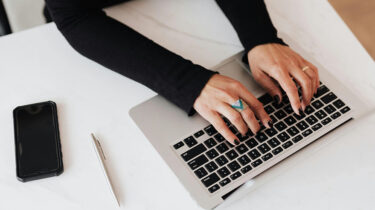 Close view of someone's hands on their keyboard as they work on a home-based typing side hustle.