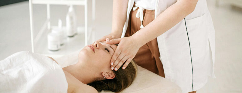 Hands of a professional massage therapist giving a head massage to a client who's lying on a massage table