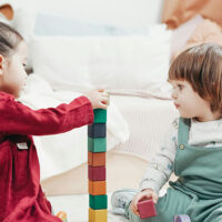 Two preschool-aged toddlers playing with colored blocks at a home daycare