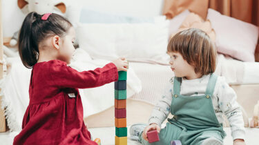 Two preschool-aged toddlers playing with colored blocks at a home daycare