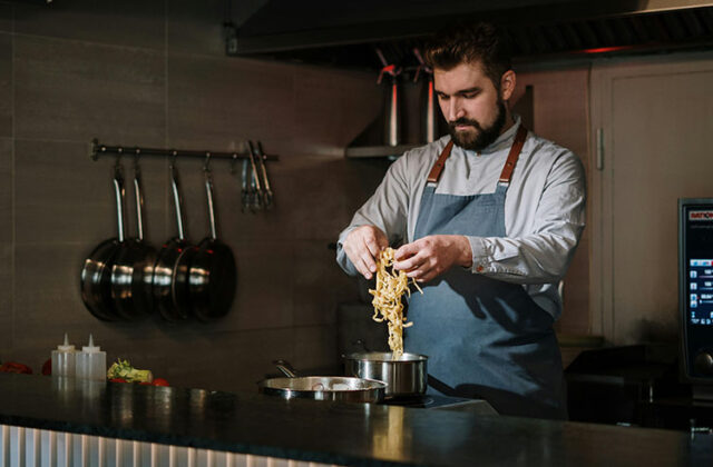 Personal chef in a home kitchen cooking noodles on a stovetop