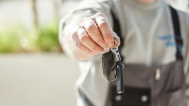 Vehicle owner holding out a car key in a key exchange to lease their car for money