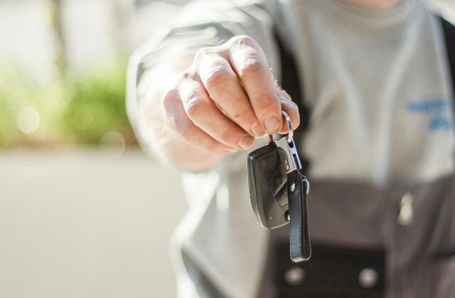 Vehicle owner holding out a car key in a key exchange to lease their car for money