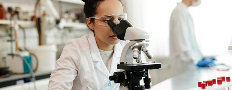 Scientist looking into a microscope in a lab.