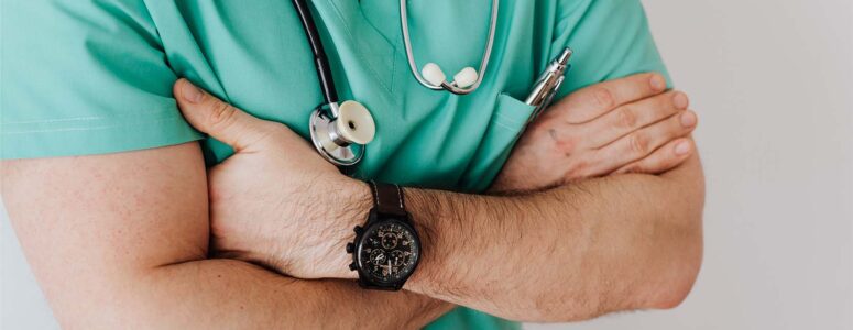 Close view of a physician dressed in blue scrubs.