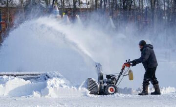 Man pushing a snowblower for his snow removal side hustle.