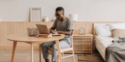 Freelance writer sitting at his desk AI tools on his laptop to write an assignment.