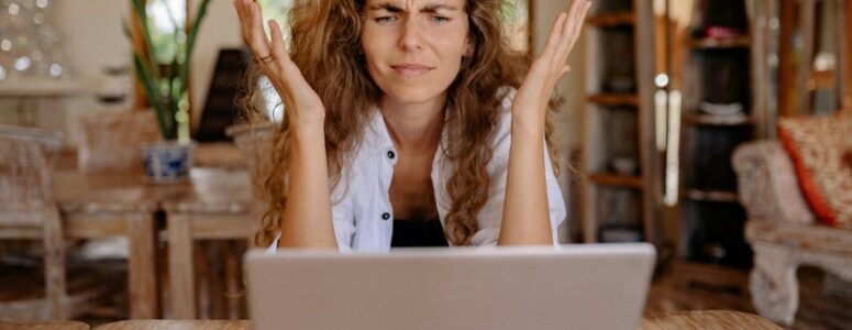 A frustrated job seeker staring in confusion at a fake remote job listing on computer.