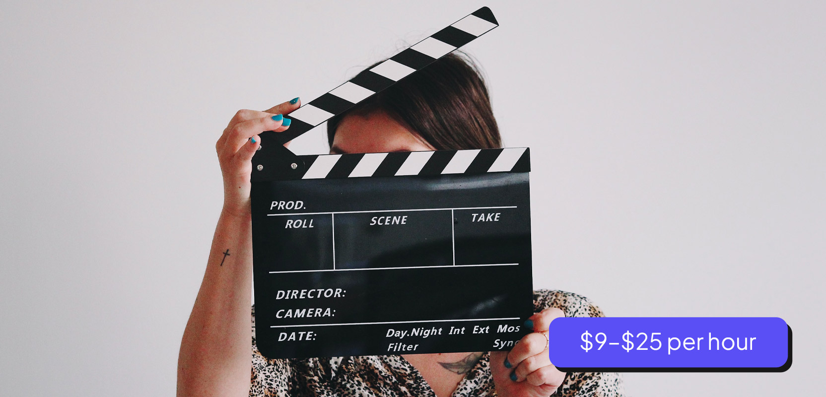 Part-time model standing behind clapperboard before going on-camera for her side hustle