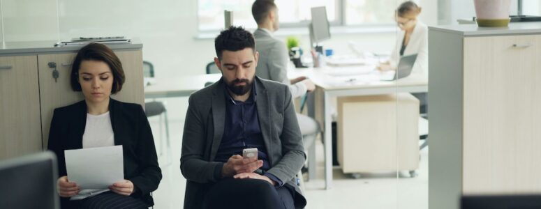 A man sitting in an office waiting to be called for a job interview.
