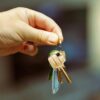 Property owner holding out house keys for a renter to give to Airbnb guests