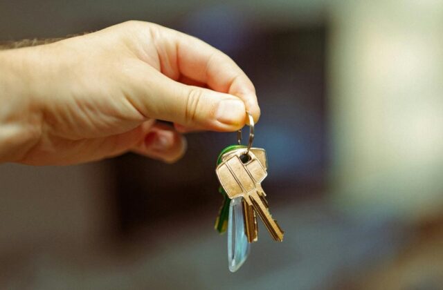 Property owner holding out house keys for a renter to give to Airbnb guests