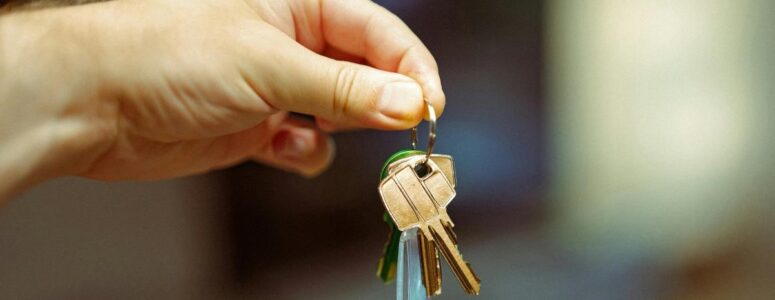 Property owner holding out house keys for a renter to give to Airbnb guests