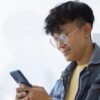 A man smiling and using his phone.