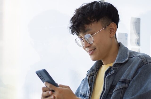A man smiling and using his phone.