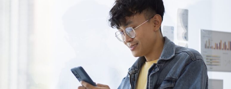 A man smiling and using his phone.