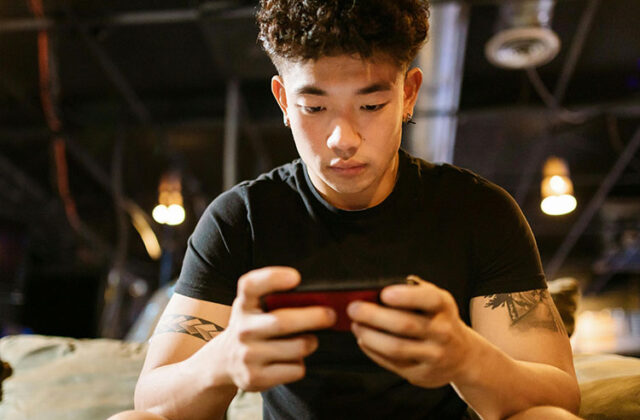 Man sitting on a couch with his smartphone using apps that pay you to sign up.