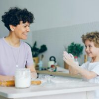 Professional nanny or babysitter doing a home baking activity with a young child