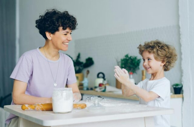 Professional nanny or babysitter doing a home baking activity with a young child