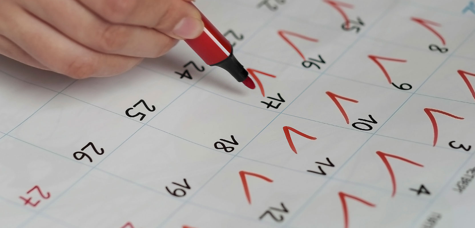 Closeup of a freelance writer checking off dates on a calendar