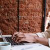 Blogger at a desk with coffee, typing up a blog post with one of the top blogging platforms