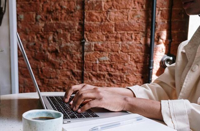 Blogger at a desk with coffee, typing up a blog post with one of the top blogging platforms