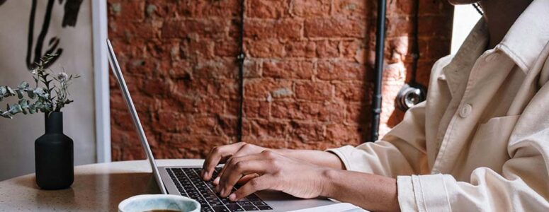 Blogger at a desk with coffee, typing up a blog post with one of the top blogging platforms