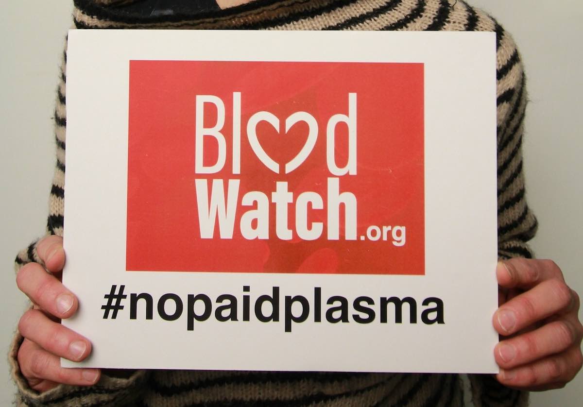 Close view of a woman holding a BloodWatch advocacy sign.