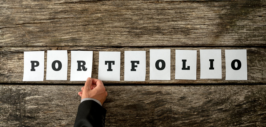 Paper slips spelling out the word Portfolio on a wooden background