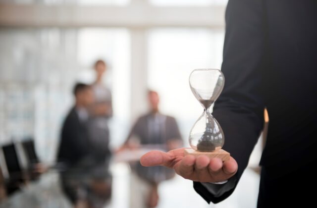 Close view of a businessman holding an hourglass.