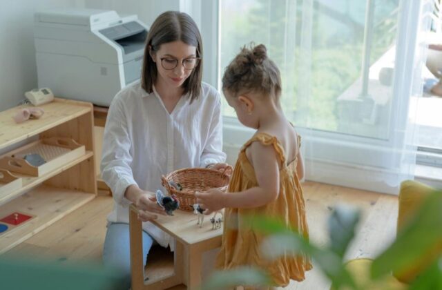 Care.com babysitter sitting in front of a child at a small, square table with a basket full of toy animals