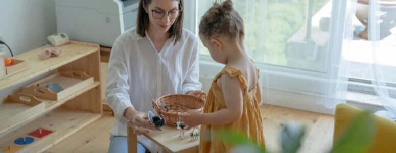 Care.com babysitter sitting in front of a child at a small, square table with a basket full of toy animals