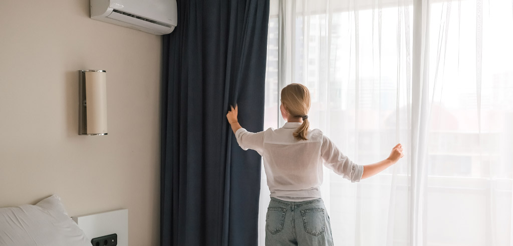 Woman adjusting the curtains on a property she's renting on Airbnb for her side hustle