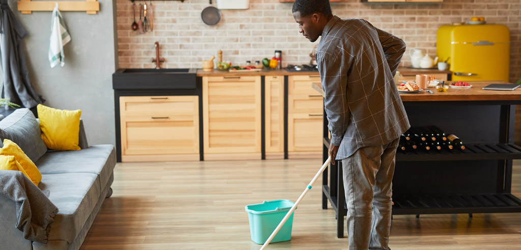 Man cleaning a floor with a mop for his part-time housekeeping side hustle