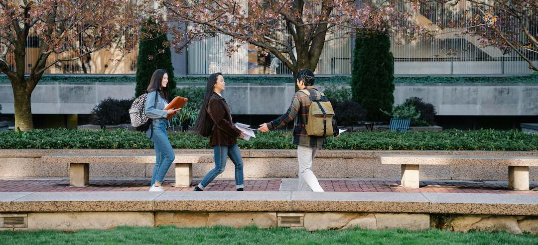 Three students walking on a college campus.