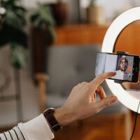 Content creator filming a video on a phone mounted in the center of a ring light