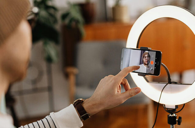 Content creator filming a video on a phone mounted in the center of a ring light