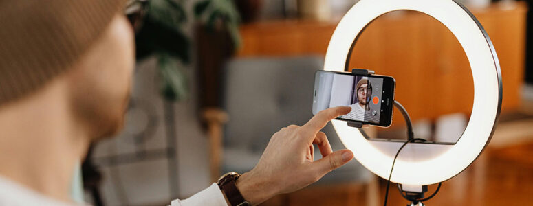 Content creator filming a video on a phone mounted in the center of a ring light